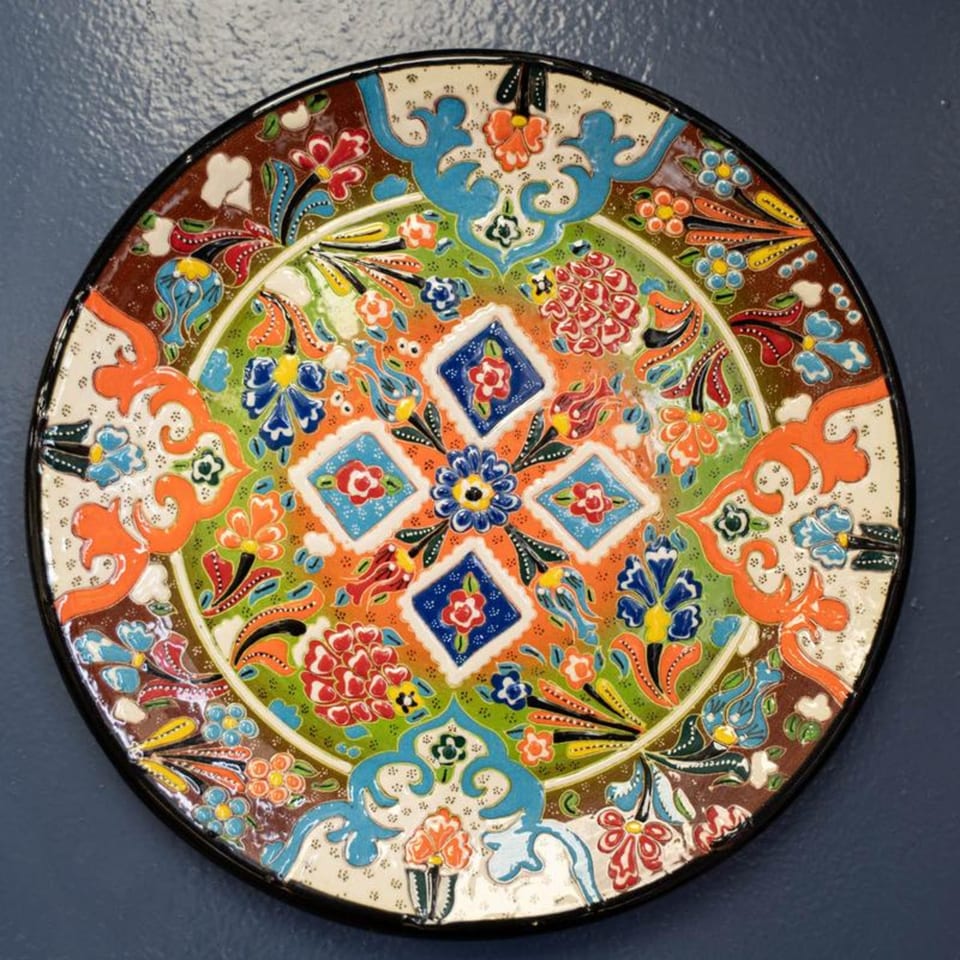 A vibrant, hand-painted Mediterranean decorative plate with intricate floral and geometric patterns.