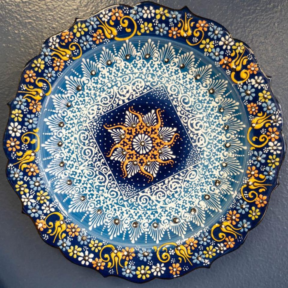 A decorative blue and white Mediterranean plate with intricate floral and geometric patterns in yellow and orange.